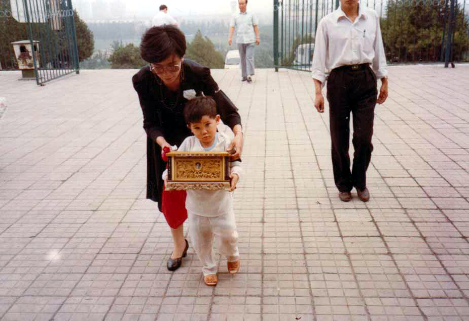 妻子與兒子手捧于地的骨灰盒