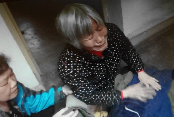 刘洪涛的母亲齐国香拿着装有她给儿子缝制的衣服的包袱，泣不成声（2013年）